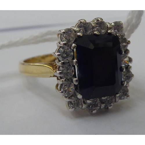 150 - A 9ct gold ring, set with an elevated sapphire, surrounded by cubic zirconias