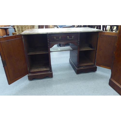 164 - A late Victorian design mahogany desk with a marble top, over a drawer and two cupboard doors, on a ... 