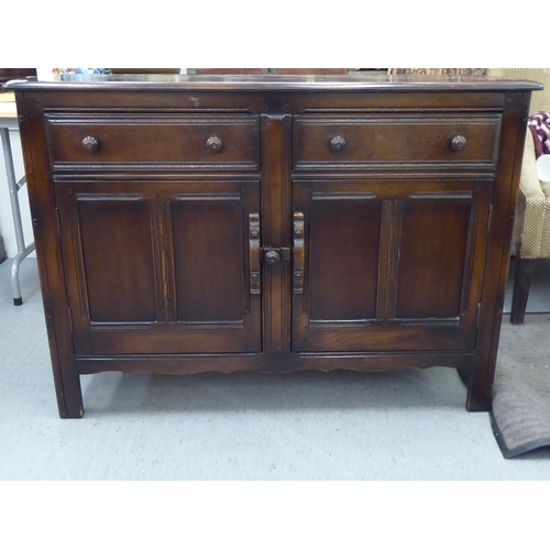 173 - A (probably) Ercol dark stained elm sideboard with a pair of frieze drawers, over two panelled doors... 