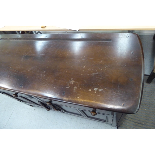 173 - A (probably) Ercol dark stained elm sideboard with a pair of frieze drawers, over two panelled doors... 