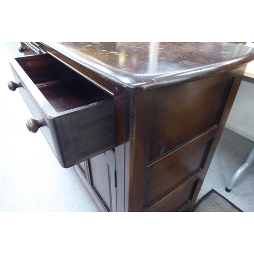 173 - A (probably) Ercol dark stained elm sideboard with a pair of frieze drawers, over two panelled doors... 