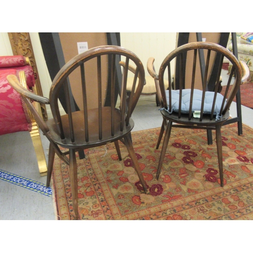 176 - A pair of Ercol stained beech and elm framed hoop and stick back, open arm chairs, the solid seats r... 