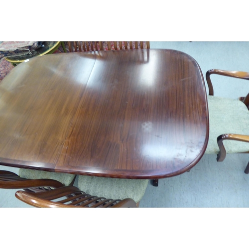 180 - A modern rosewood effect twin pedestal dining table, the top with round corners, raised on splayed s... 