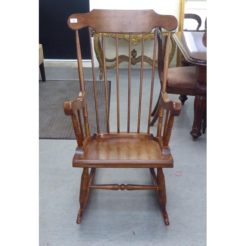 181 - A modern stained beech framed open arm, spindle back rocking chair 