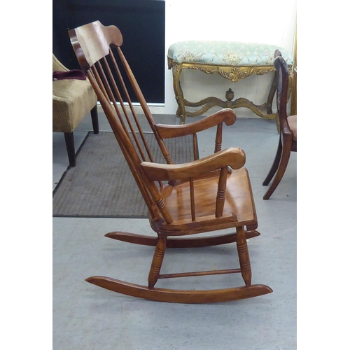 181 - A modern stained beech framed open arm, spindle back rocking chair 