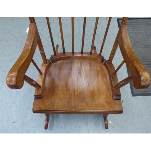 181 - A modern stained beech framed open arm, spindle back rocking chair 