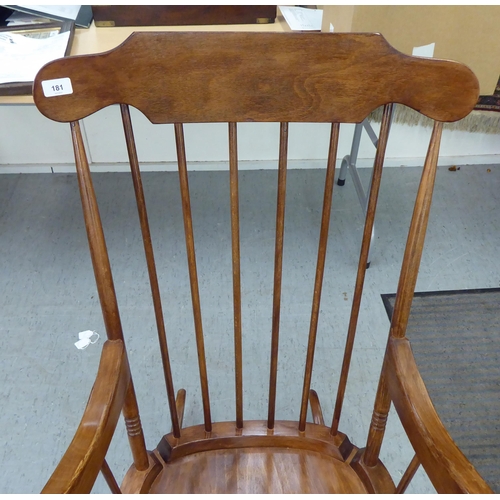 181 - A modern stained beech framed open arm, spindle back rocking chair 