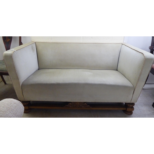 184 - A 1920s/1930s and later fabric upholstered two person settee with a level back and arms, raised on a... 