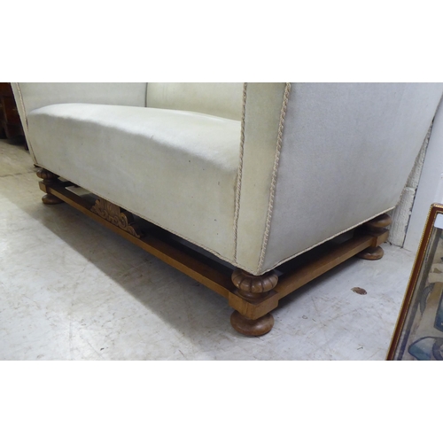 184 - A 1920s/1930s and later fabric upholstered two person settee with a level back and arms, raised on a... 