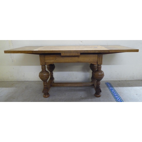 185 - A mid 20thC oak draw leaf occasional table, raised on turned, block supports, united by a stretcher&... 