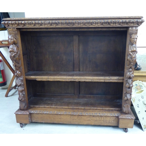 192 - An early 20thC carved oak open front two tier bookcase, on a plinth and casters  42