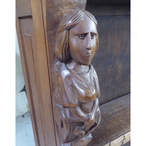 192 - An early 20thC carved oak open front two tier bookcase, on a plinth and casters  42