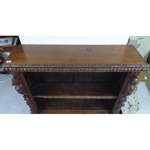 192 - An early 20thC carved oak open front two tier bookcase, on a plinth and casters  42