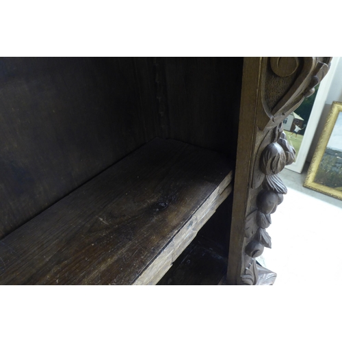 192 - An early 20thC carved oak open front two tier bookcase, on a plinth and casters  42