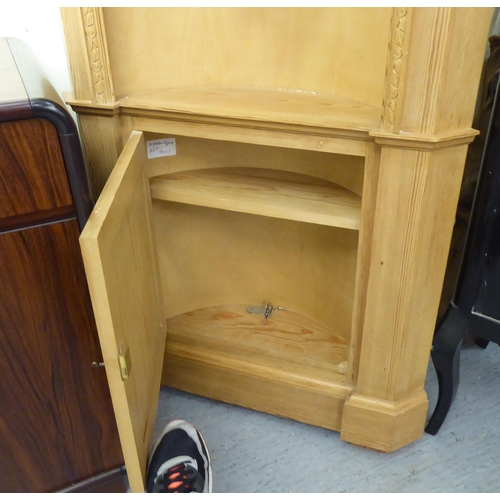 193 - A modern two tone pine, one piece corner cabinet with a concave two tier display, over a panelled do... 