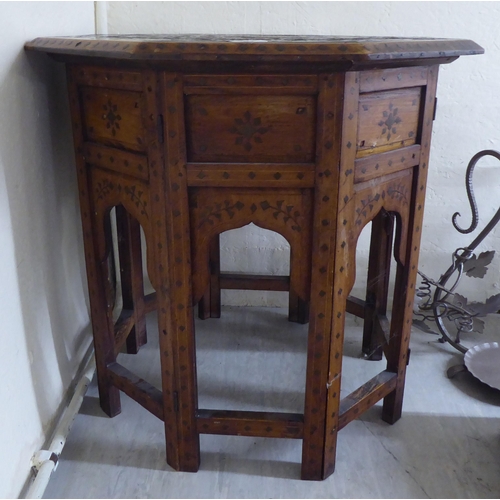 201 - An early/mid 20thC Indian brass inlaid fruitwood octagonal occasional table, on a folding underframe... 