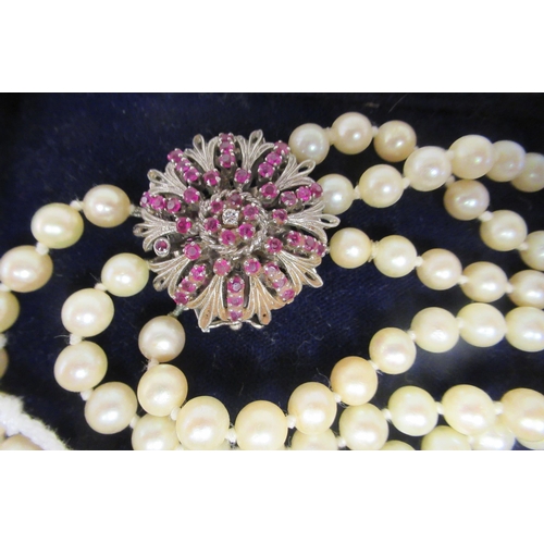 28 - A triple row pearl choker, on a white metal ruby and diamond set rosette clasp 