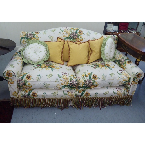 299 - A Peter Dudgeon two person cottage design settee with scrolled arms, upholstered in floral patterned... 