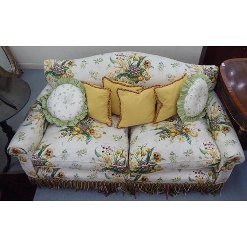 299 - A Peter Dudgeon two person cottage design settee with scrolled arms, upholstered in floral patterned... 