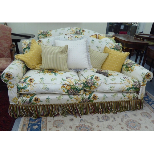 300 - A Peter Dudgeon two person cottage design settee with scrolled arms, upholstered in floral patterned... 