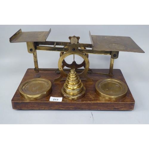 332 - Early 20thC lacquered brass beam balance type postal scales, on a rectangular oak platform, the two ... 