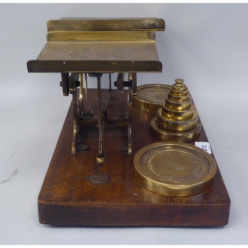 332 - Early 20thC lacquered brass beam balance type postal scales, on a rectangular oak platform, the two ... 