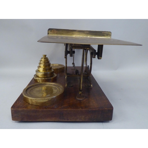 332 - Early 20thC lacquered brass beam balance type postal scales, on a rectangular oak platform, the two ... 