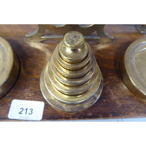 332 - Early 20thC lacquered brass beam balance type postal scales, on a rectangular oak platform, the two ... 