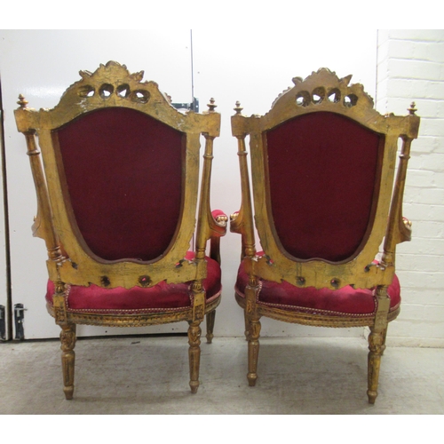 360 - A pair of late Victorian style gilded, moulded and carved salon chairs with open arms and part butto... 