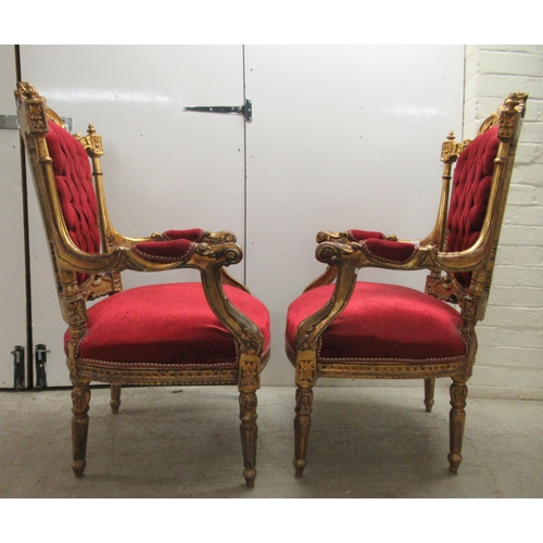 360 - A pair of late Victorian style gilded, moulded and carved salon chairs with open arms and part butto... 