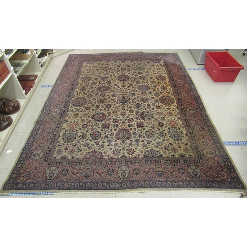 402 - A Persian carpet, profusely decorated with vases, flora and foliage, on a multi-coloured ground ... 