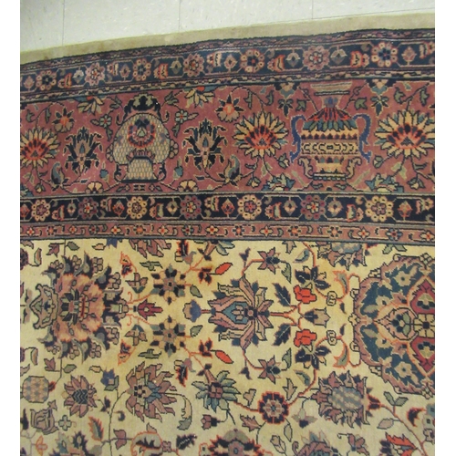 402 - A Persian carpet, profusely decorated with vases, flora and foliage, on a multi-coloured ground ... 