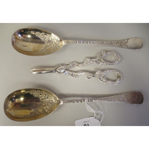 10 - A pair of late Victorian silver plated fruit spoons with decoratively scroll engraved ornament; and ... 