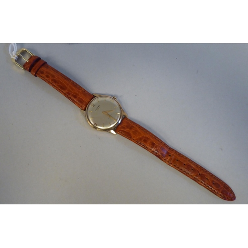 11 - A Longines 9ct gold cased wristwatch, faced by an Arabic and baton dial, on a stitched mid brown hid... 