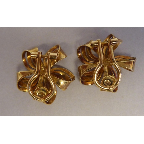 111 - A pair of textured 18ct gold ribbon tied floral clip-on earrings, claw set with sapphires