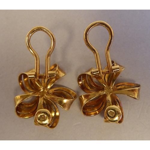 111 - A pair of textured 18ct gold ribbon tied floral clip-on earrings, claw set with sapphires