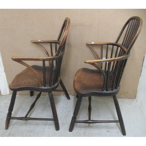 132 - A matched pair of early 19thC beech and elm framed low hoop and spindled back Windsor elbow chairs, ... 