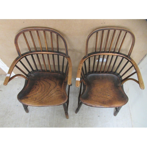 132 - A matched pair of early 19thC beech and elm framed low hoop and spindled back Windsor elbow chairs, ... 