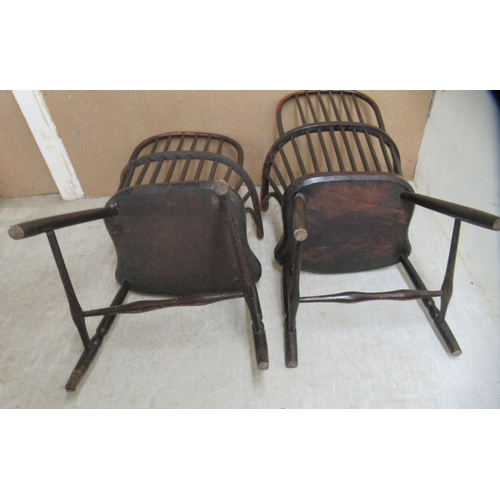 132 - A matched pair of early 19thC beech and elm framed low hoop and spindled back Windsor elbow chairs, ... 