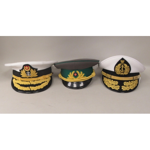 148 - Nine various unidentified foreign military officers' peaked uniform hats, decorated with emblems and... 