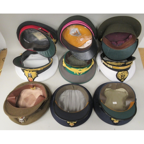 148 - Nine various unidentified foreign military officers' peaked uniform hats, decorated with emblems and... 