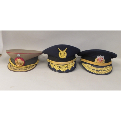 183 - Eight various foreign military officers' peaked uniform hats, decorated with emblems and braid: to i... 