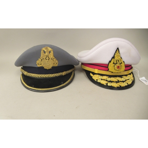 187 - Seven various foreign military officers' peaked uniform hats, decorated with emblems and braid: to i... 