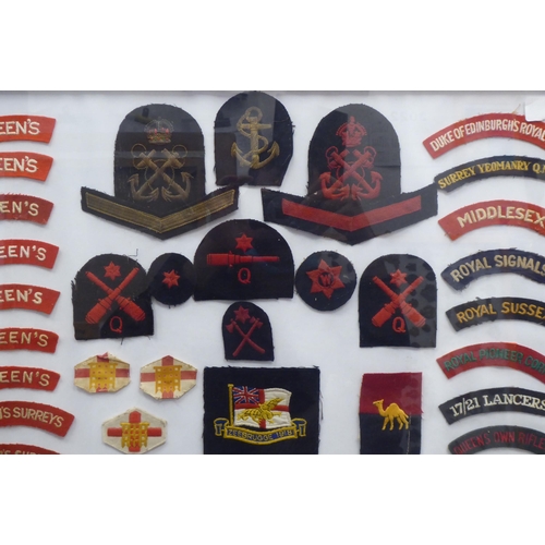 20 - A framed display of woven and other military uniform badges and similar insignia, some copies: to in... 