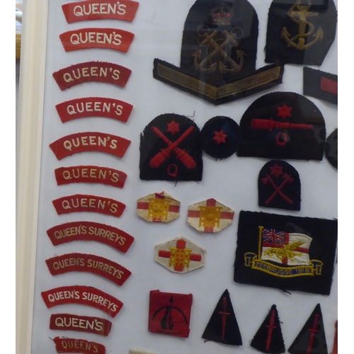 20 - A framed display of woven and other military uniform badges and similar insignia, some copies: to in... 