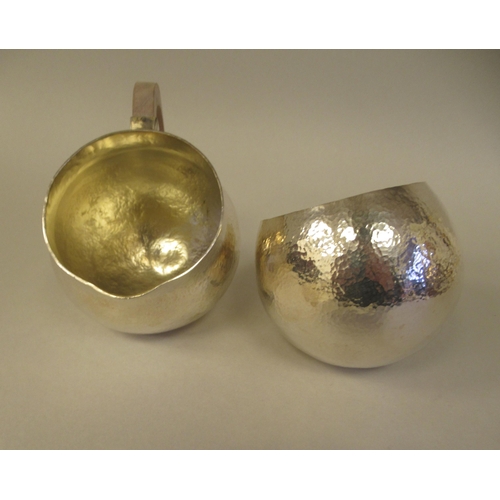 21 - An Art Deco inspired three piece spot-hammered silver tea set of spherical form  comprising a teapot... 