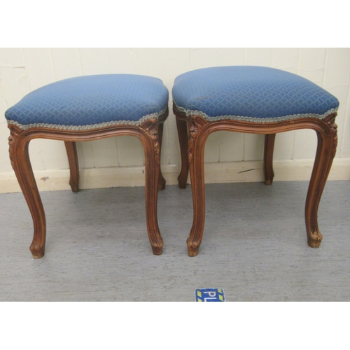 251 - A pair of 20thC carved and moulded mahogany framed and upholstered stools of serpentine outline, the... 