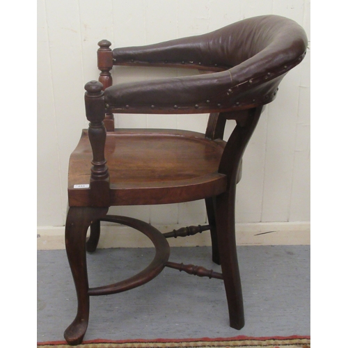 253 - A late 19th/early 20thC mahogany framed horseshoe shape desk chair, the stud upholstered rexine cres... 