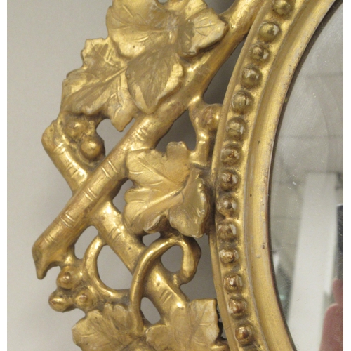 277 - A 19thC oval mirror, set in an ornately, bead carved and floral decorated, giltwood frame  18