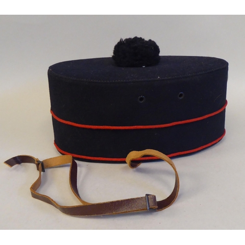 29 - A military style black pill box hat with red piping  bears a Hobson & Sons (London) label and br... 